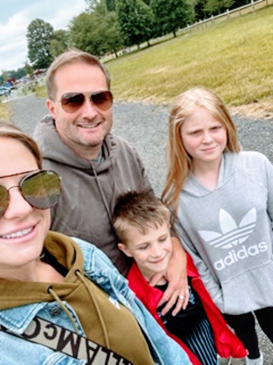 A mother stands with her husband and two children outside