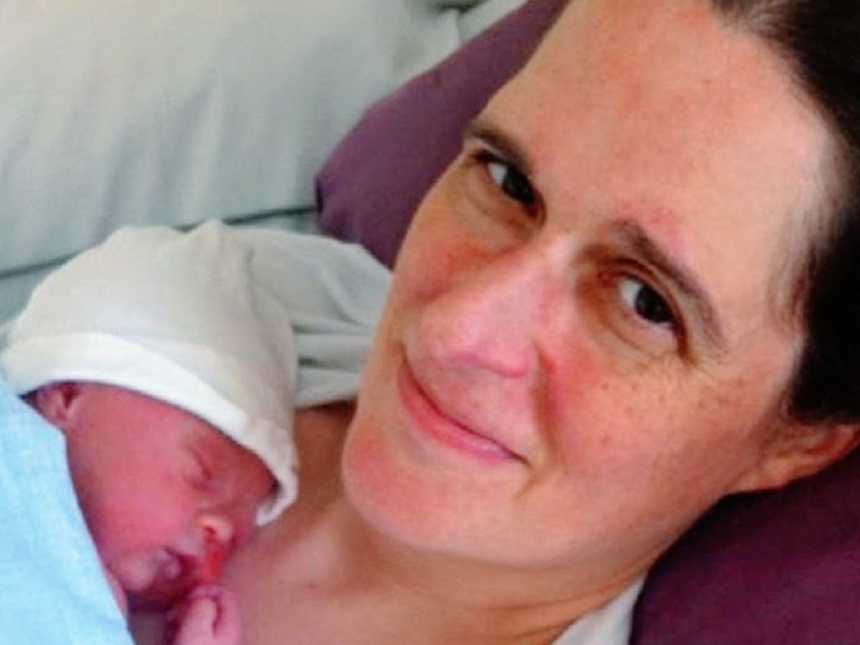 一位母亲抱着新生儿躺在医院的病床上