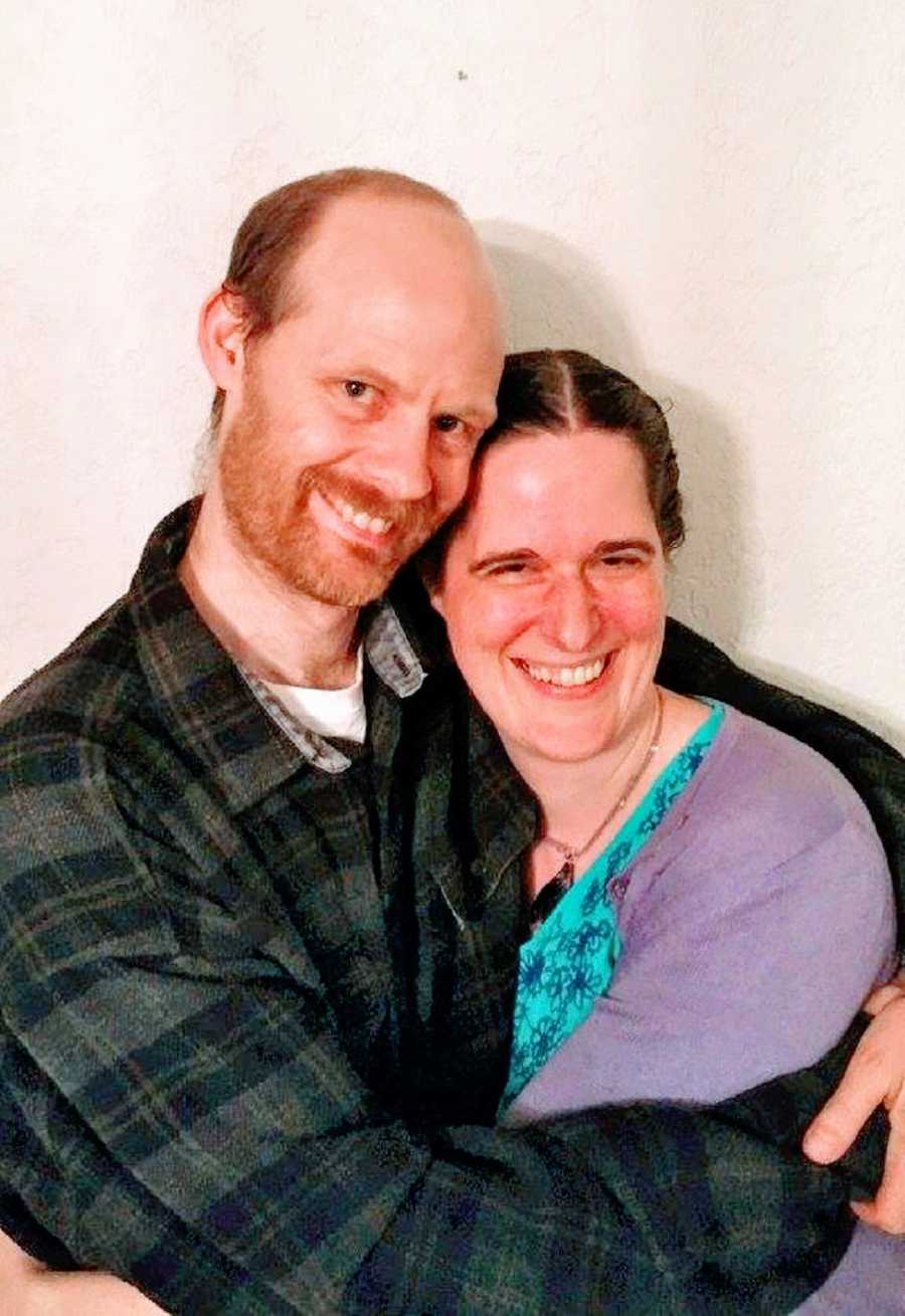 A man wraps his arms around his partner