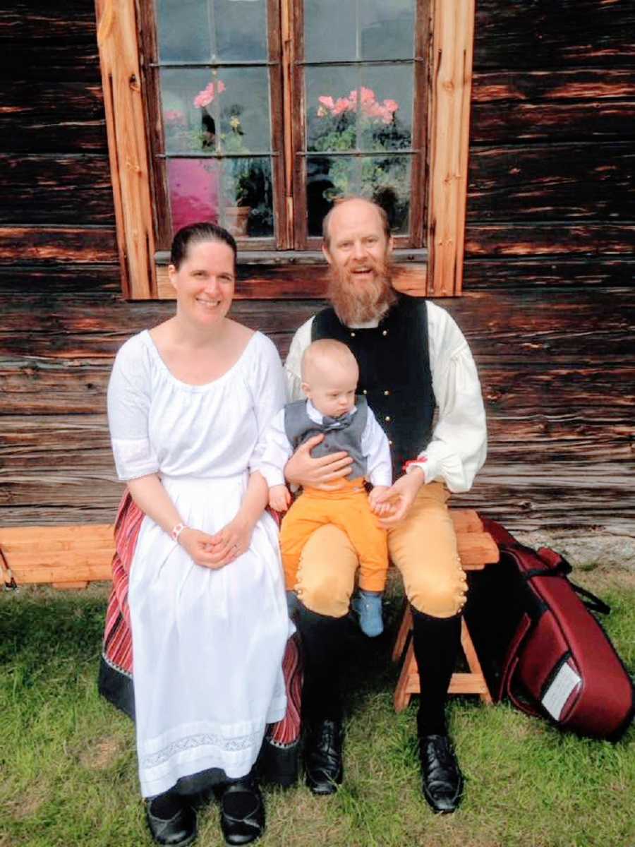 A couple sit with their young child