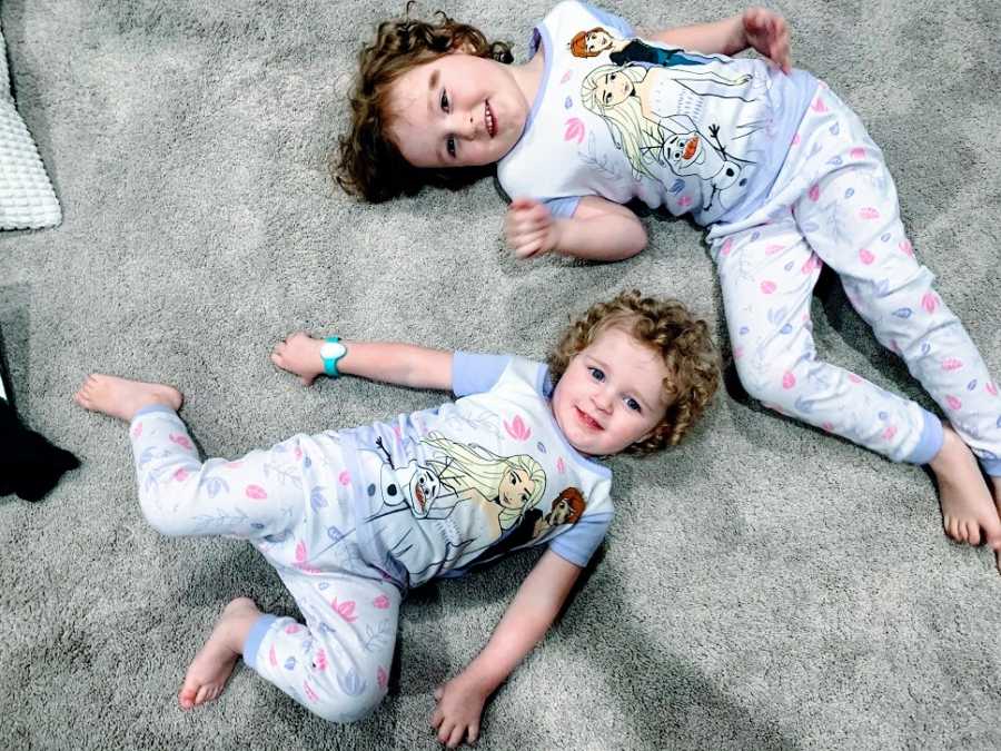 A pair of sisters lie on the floor together