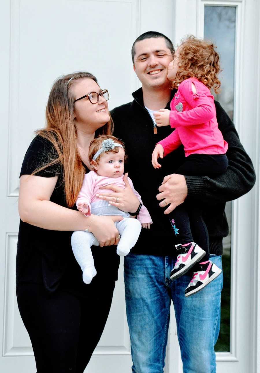 Parents stand holding their two young children