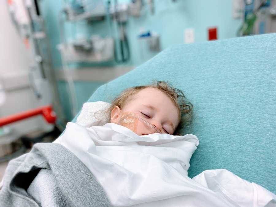 A little girl lying on a bed in a hospital