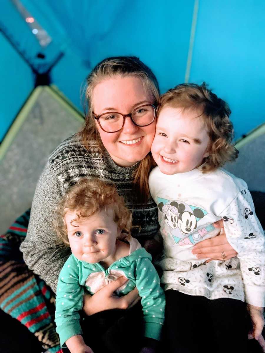 A mother holds her two daughters close to her