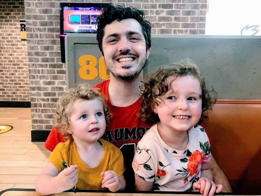 A father sits with his two daughters in a booth