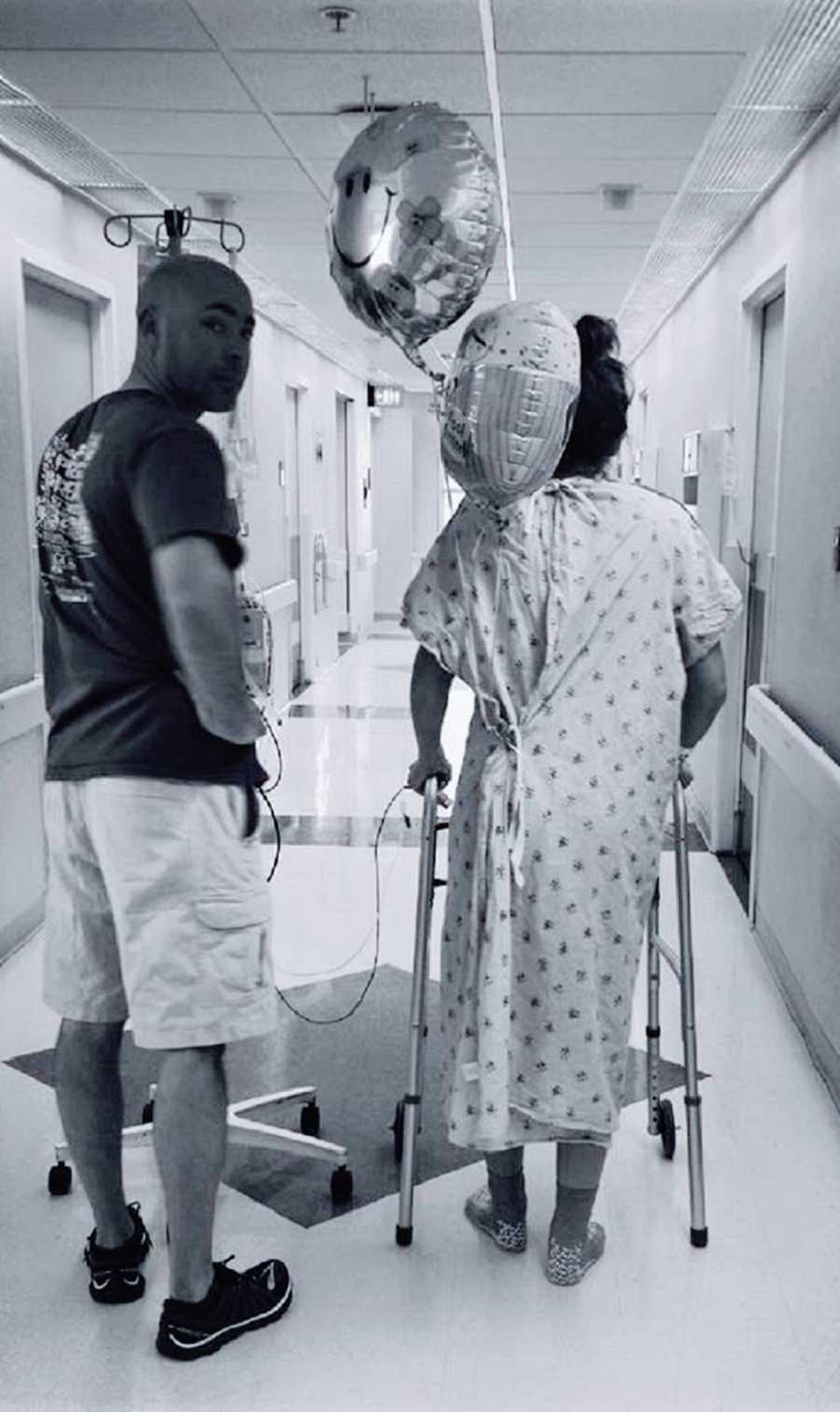 A man and a woman walk down a hospital corridor