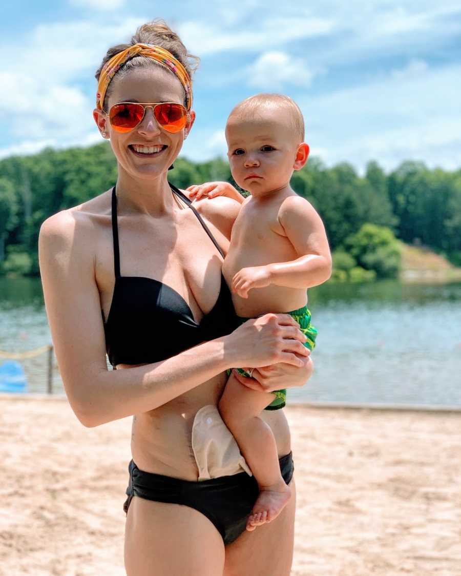 A woman with a medical bag holds her son at the beach