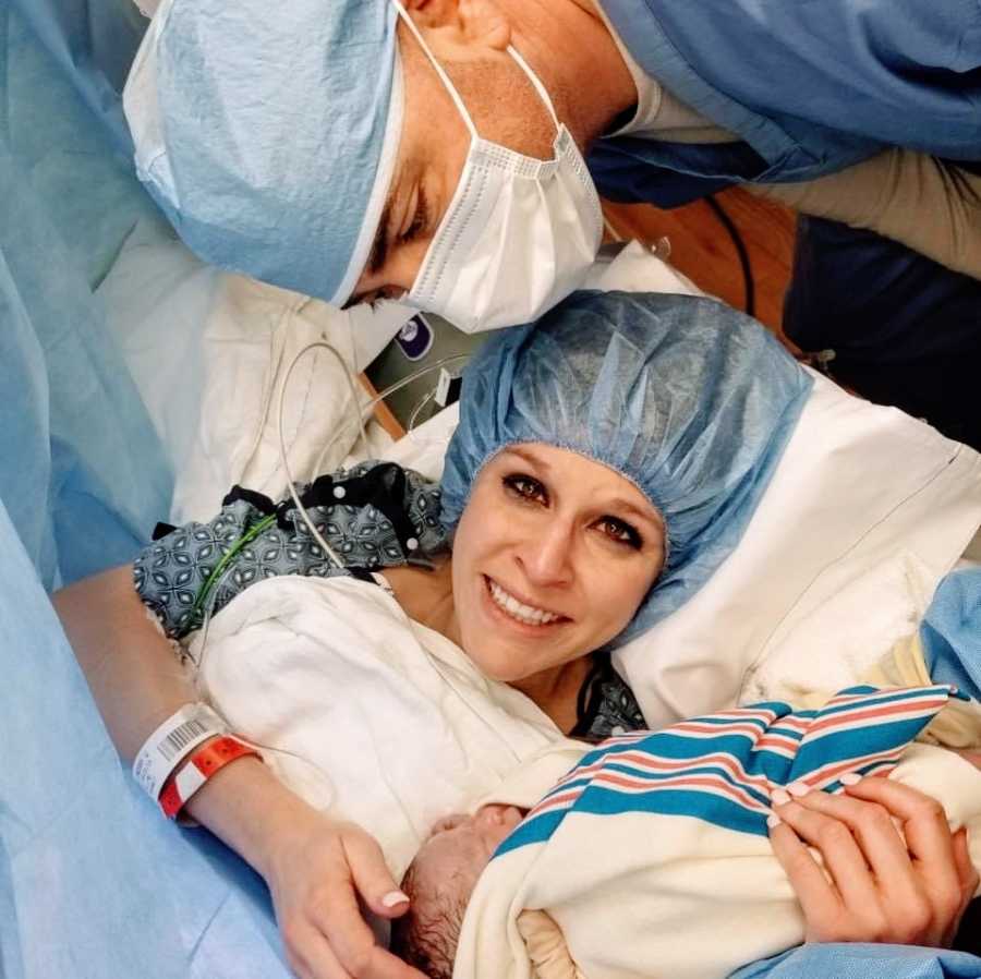 A woman sits in a hospital bed after giving birth