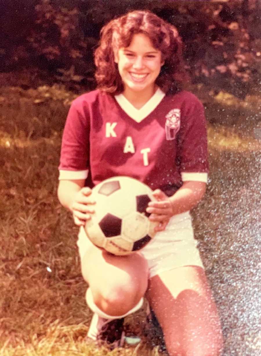 A young woman holds a soccer ball 