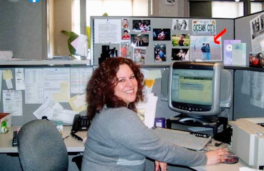A woman sits at a desk with a large computer