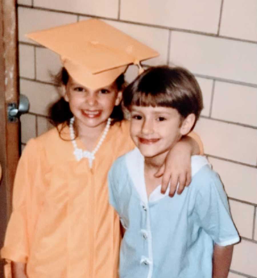 Sisters stand together, one wearing a cap and gown