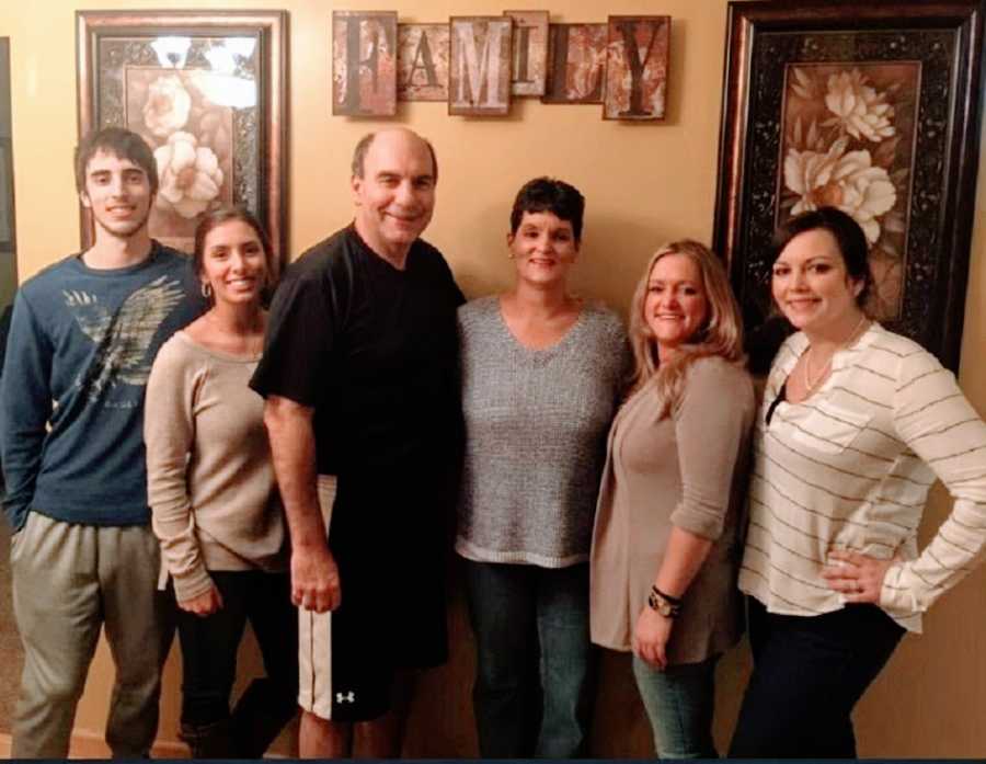 A family stand together in front of a wall