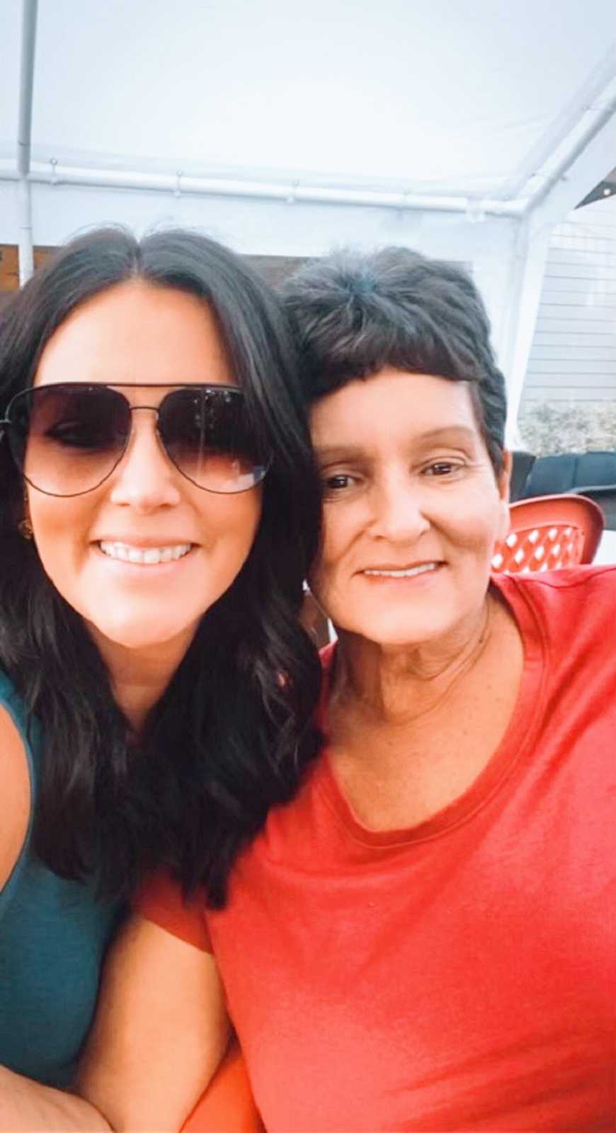 A woman and her mother sit together outside