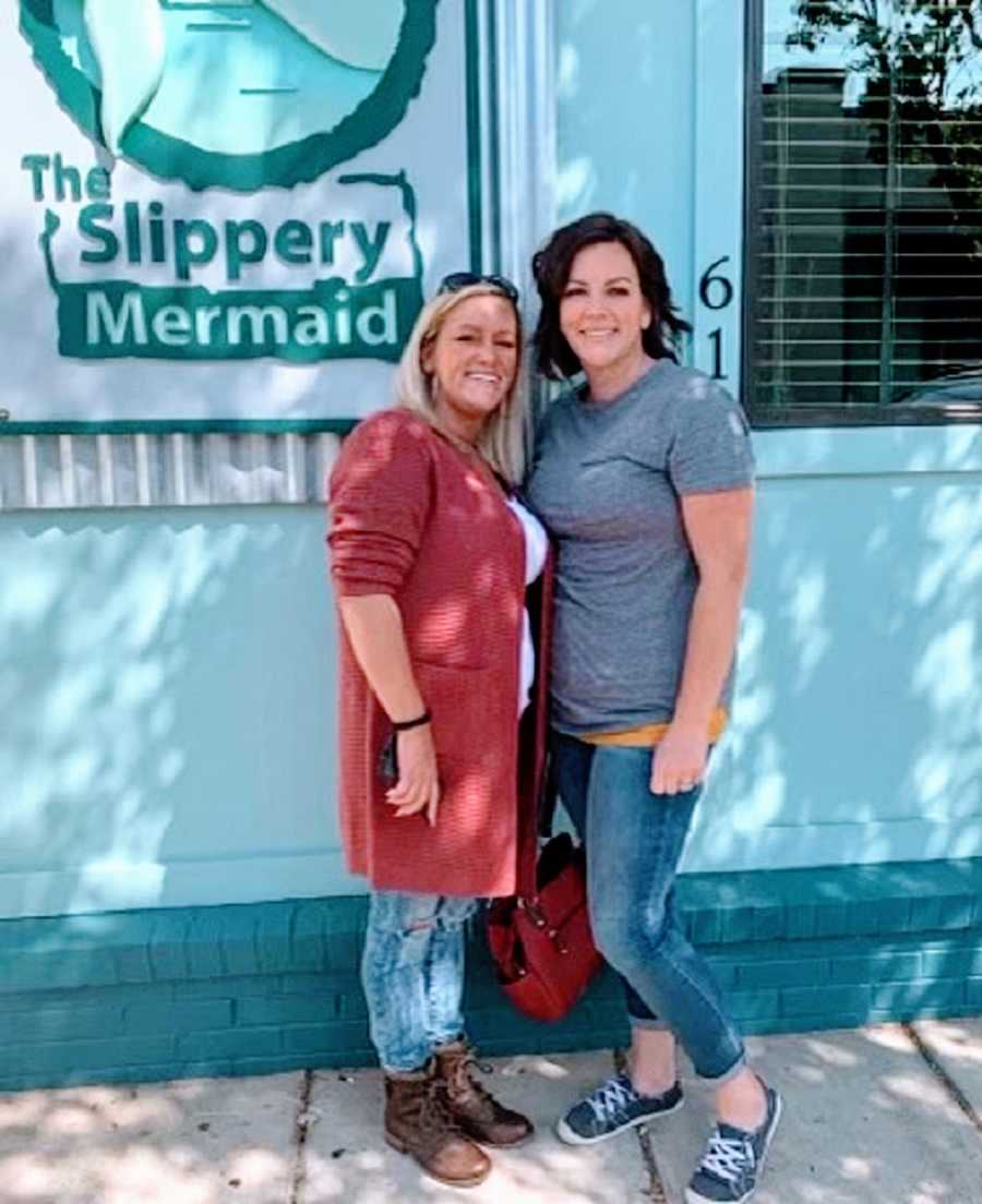 A woman and her sister stand outside of a shop