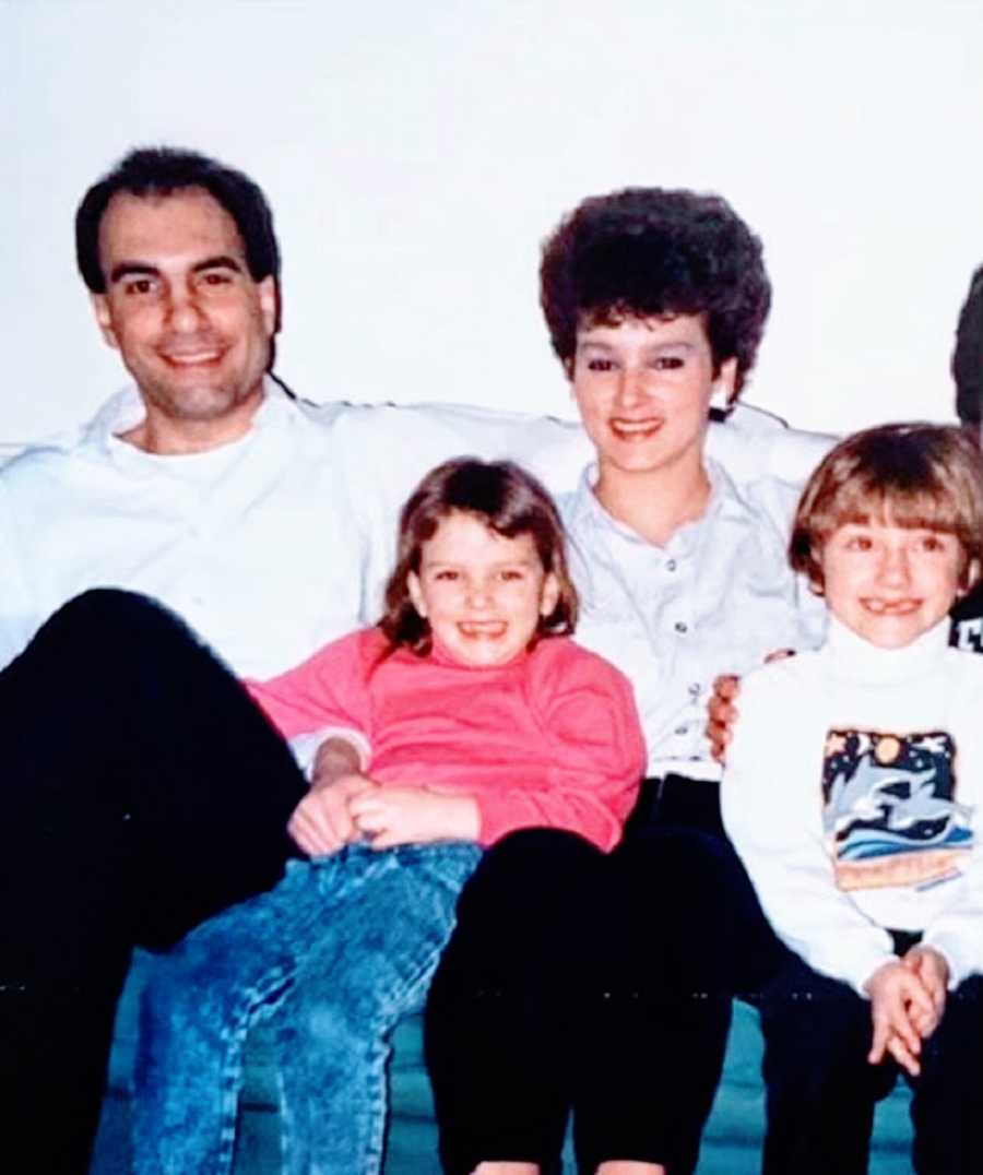 Parents sit on a couch with their two daughters