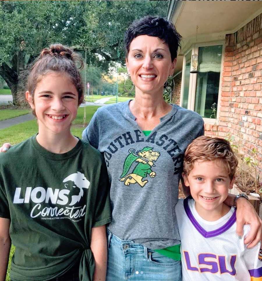 Mom with her kids smiling outside of house