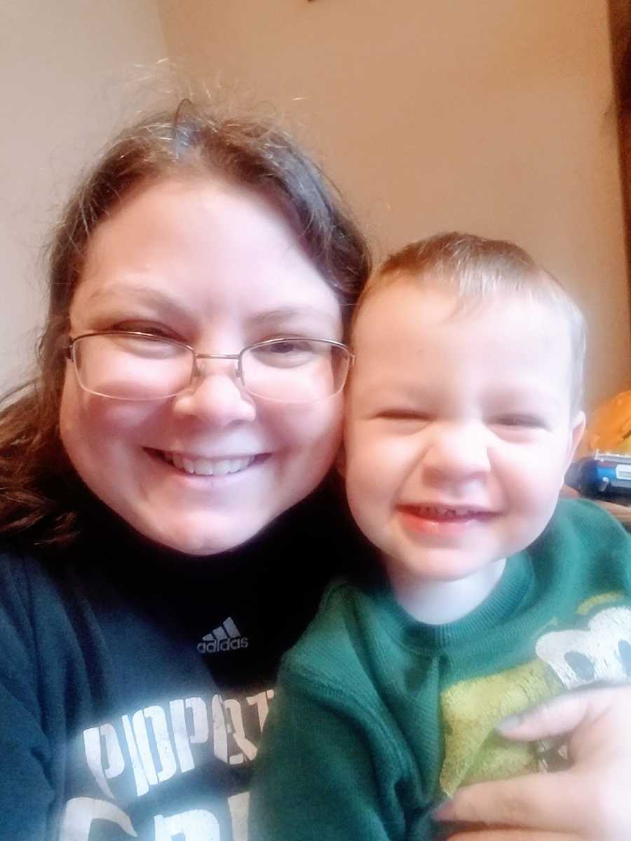 A little boy and his mom smile at the camera