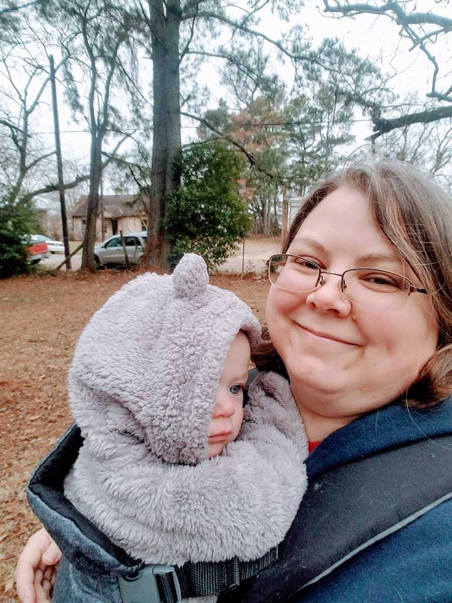 A mother holds her baby girl wearing a coat