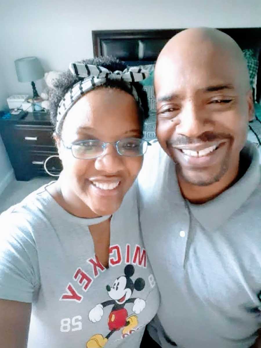 A woman and her husband stand in their bedroom