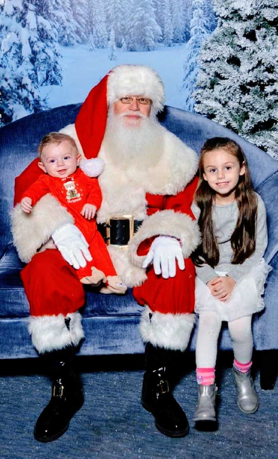 A pair of young children sit with Santa Claus