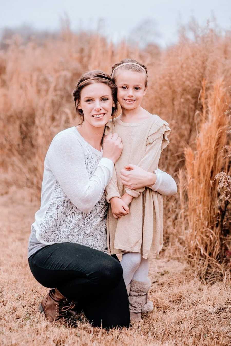 A mom and her daughter stand together in a field