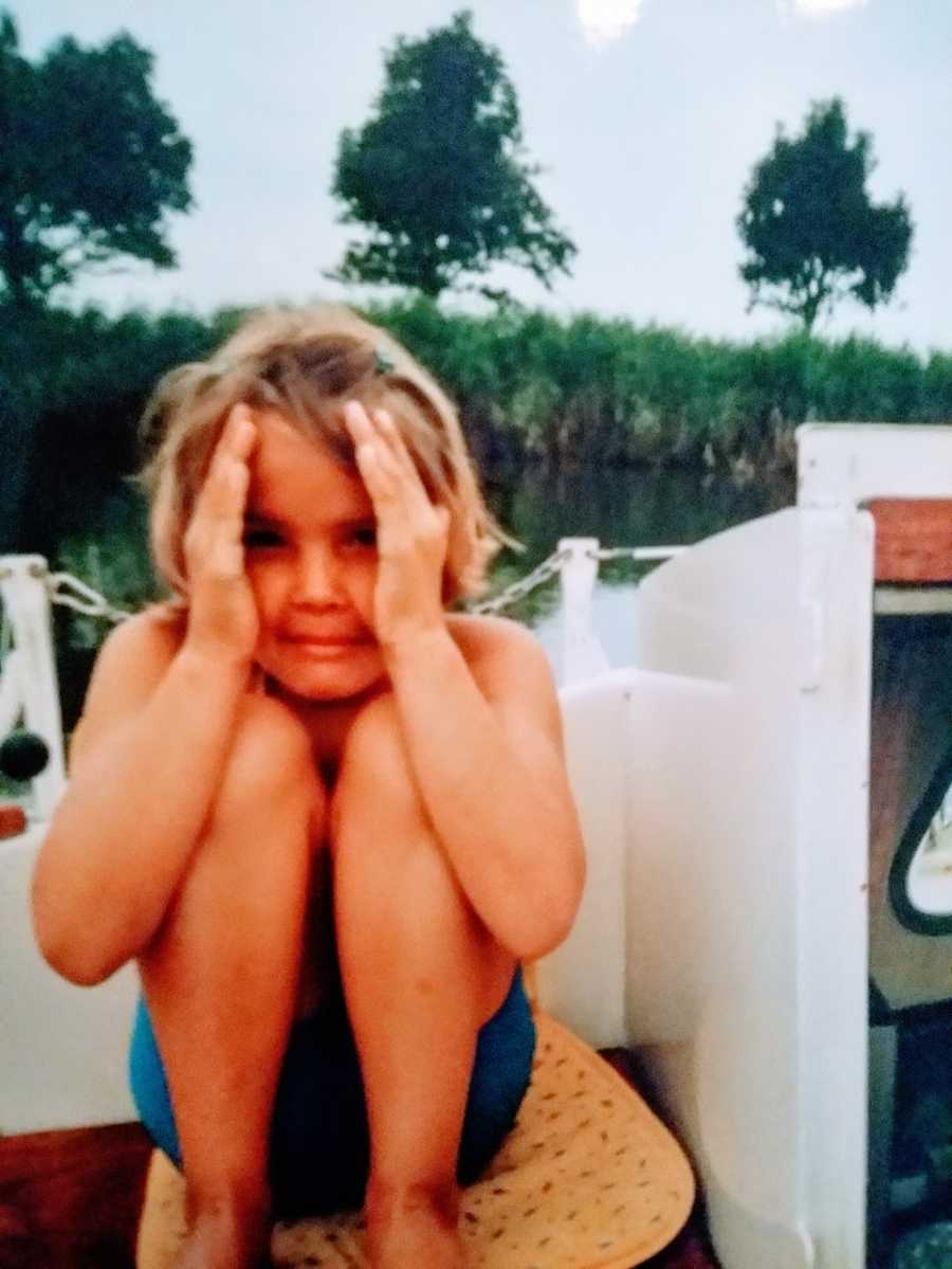 A child covers the sides of their face with their hands