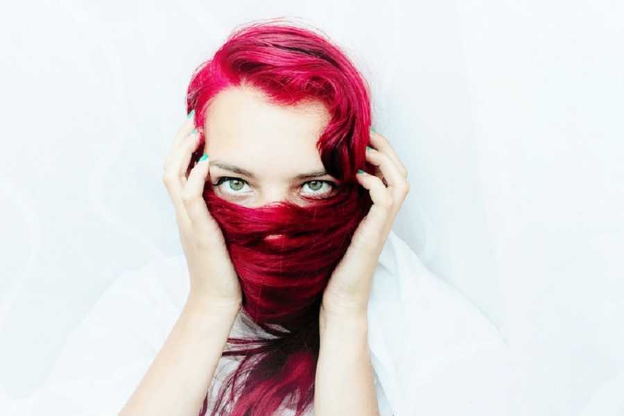 A person with red hair covers their face
