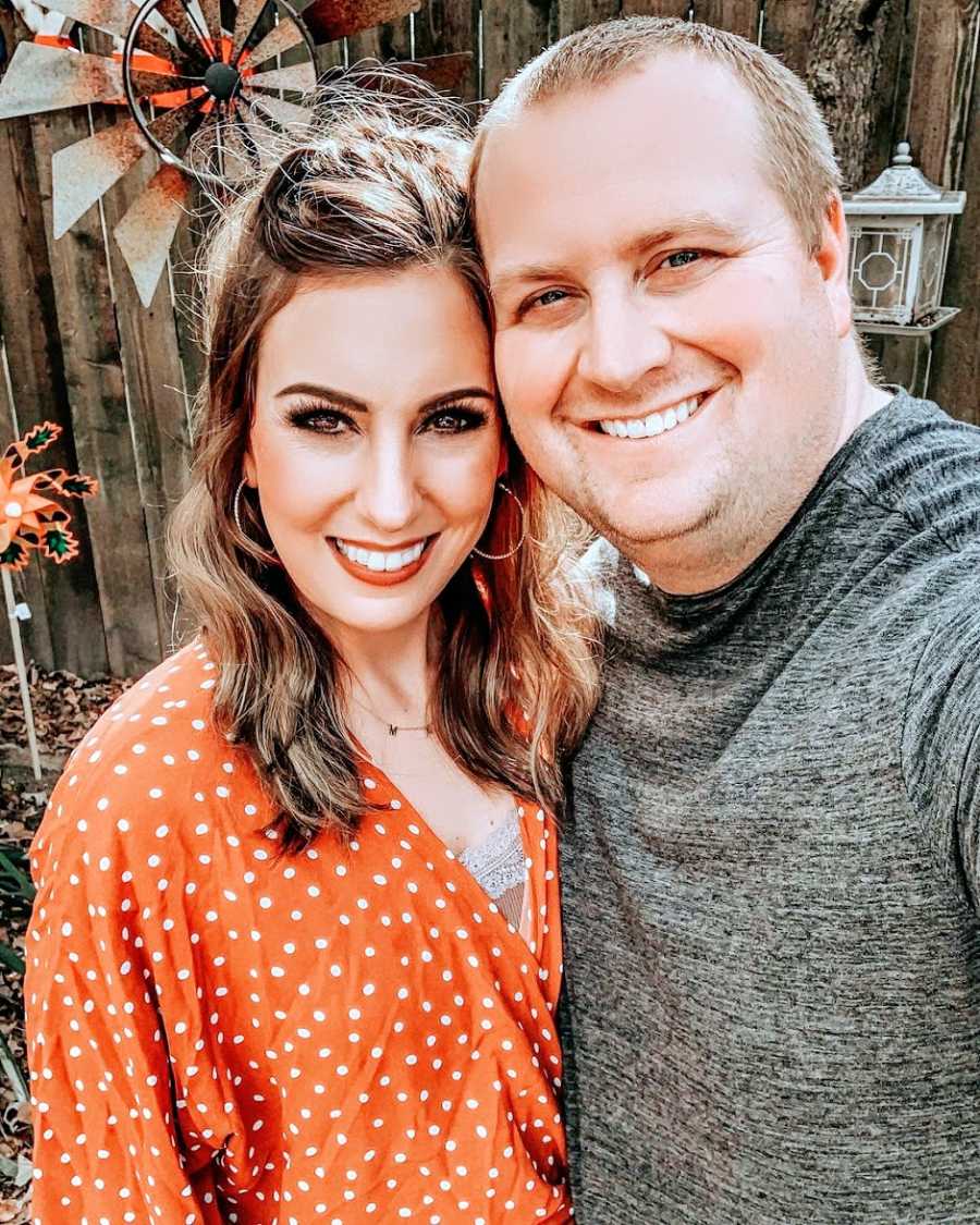 A mom and her husband stand by a fence