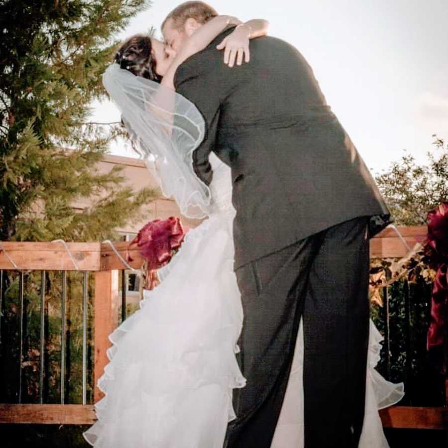 A bride and groom kiss on a balcony