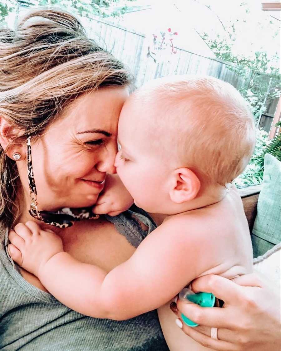 A mother presses her nose to her baby son's