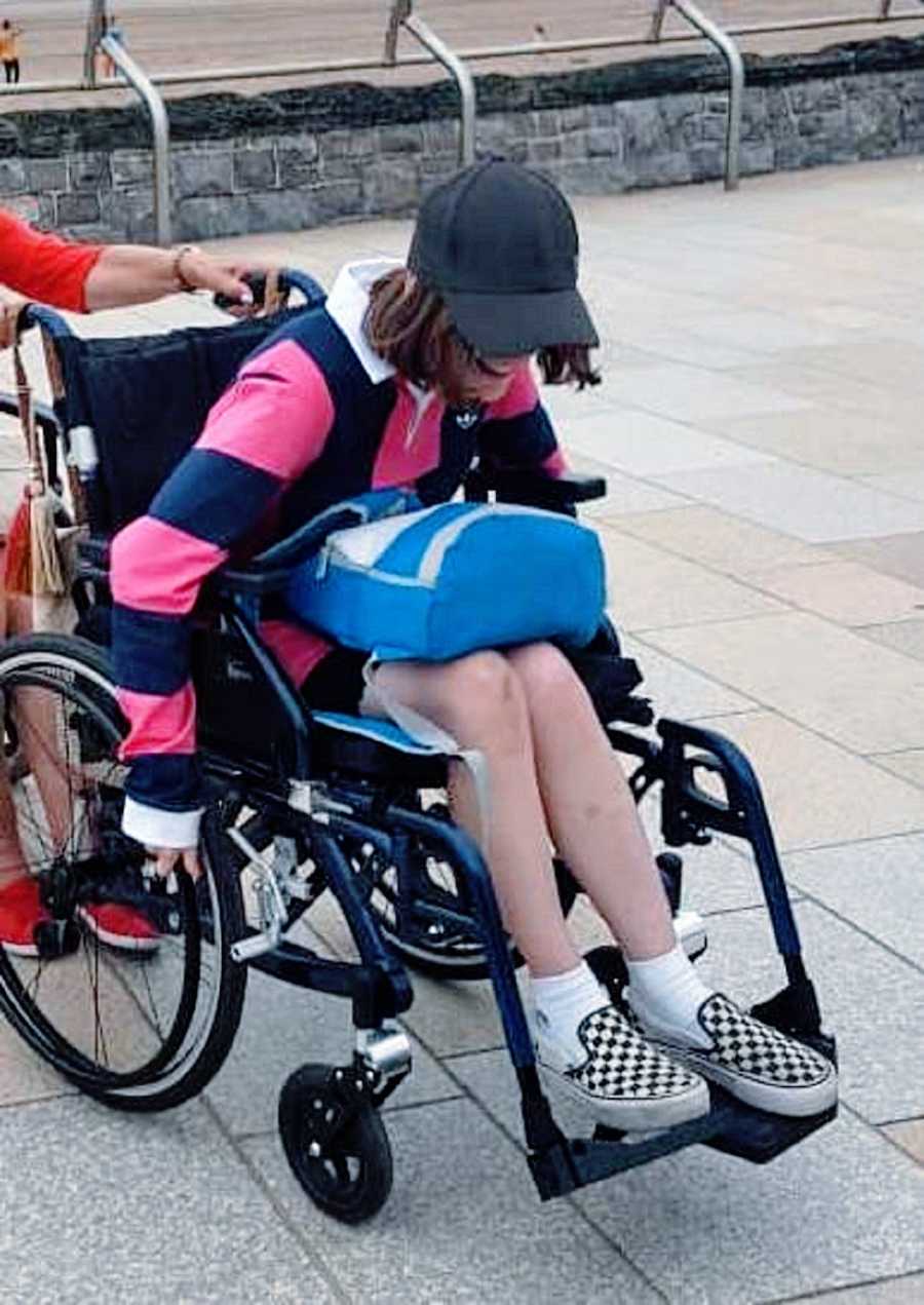 A woman in a wheelchair with a blue backpack on her lap