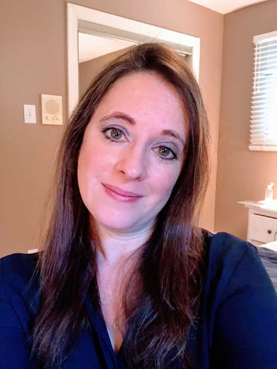 A woman with long brown hair smiles faintly