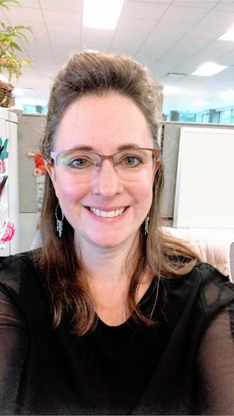 A woman wearing glasses sits in an office