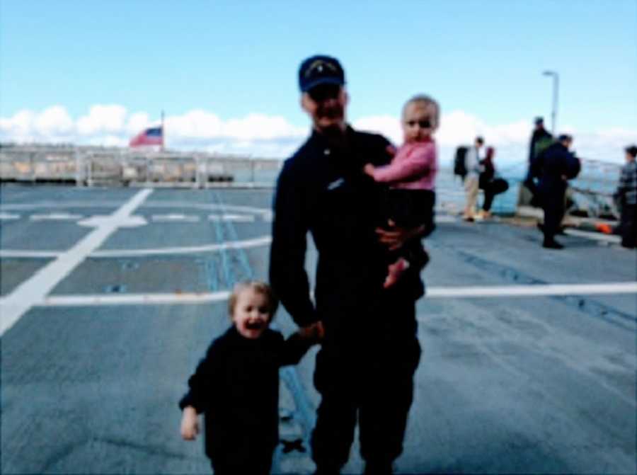 A father stands with his two children on a tarmac