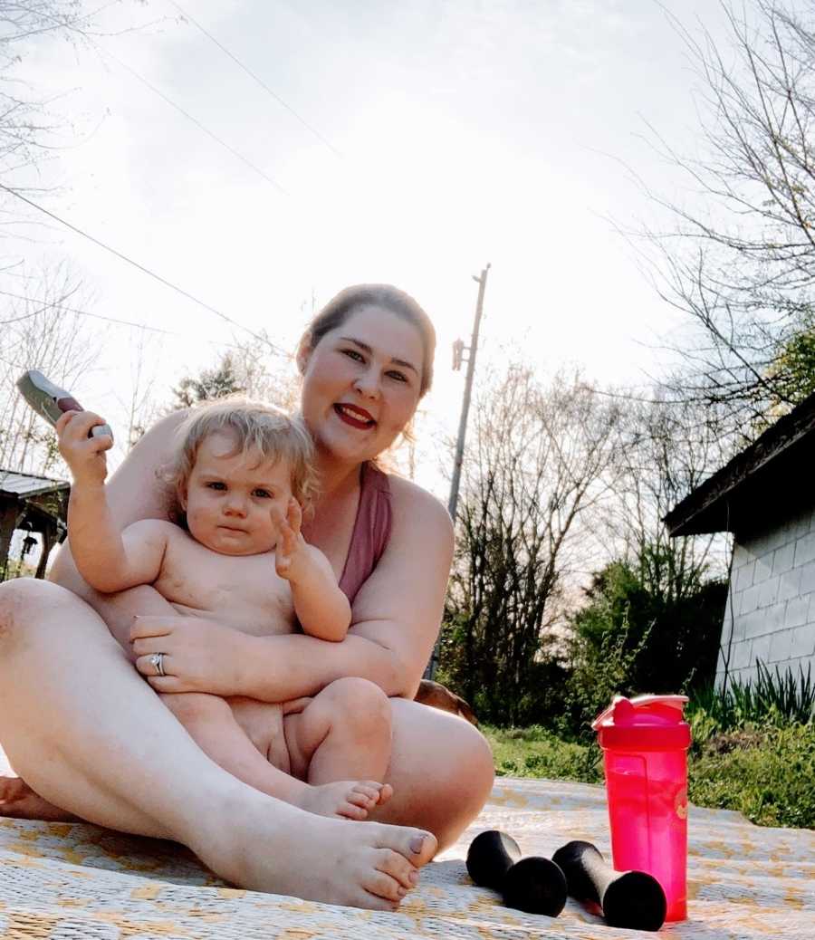 A mother holds her toddler sitting outside