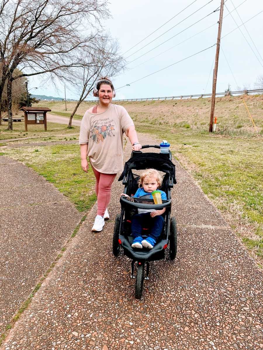 A mother takes her toddler for a walk in a stroller