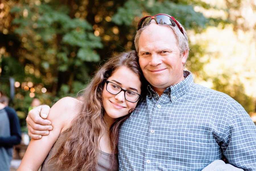 A father sits with his daughter leaning on his shoulder