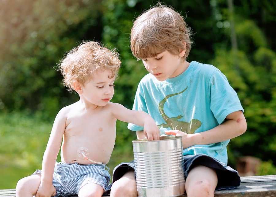 A pair of brothers play with a can outside