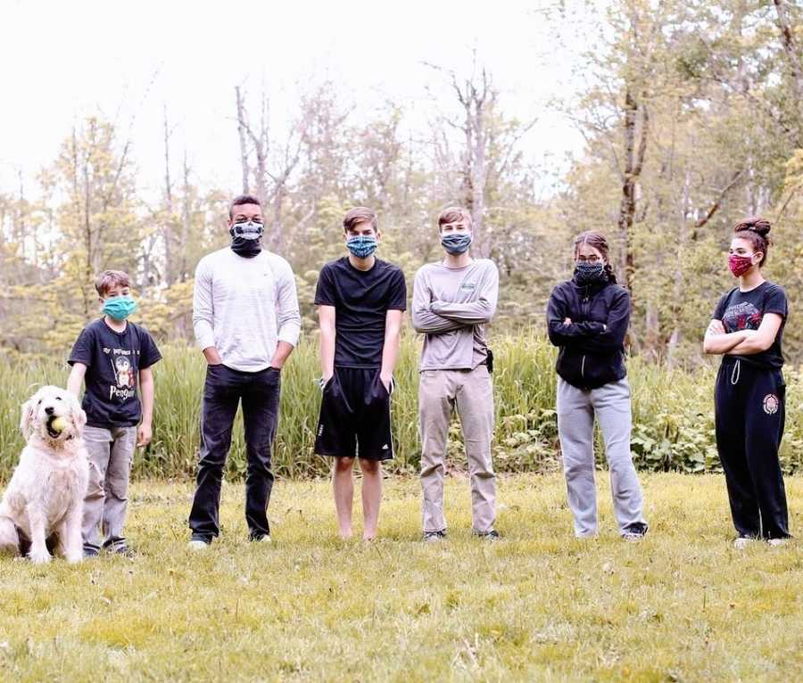 A group of siblings stand together wearing masks