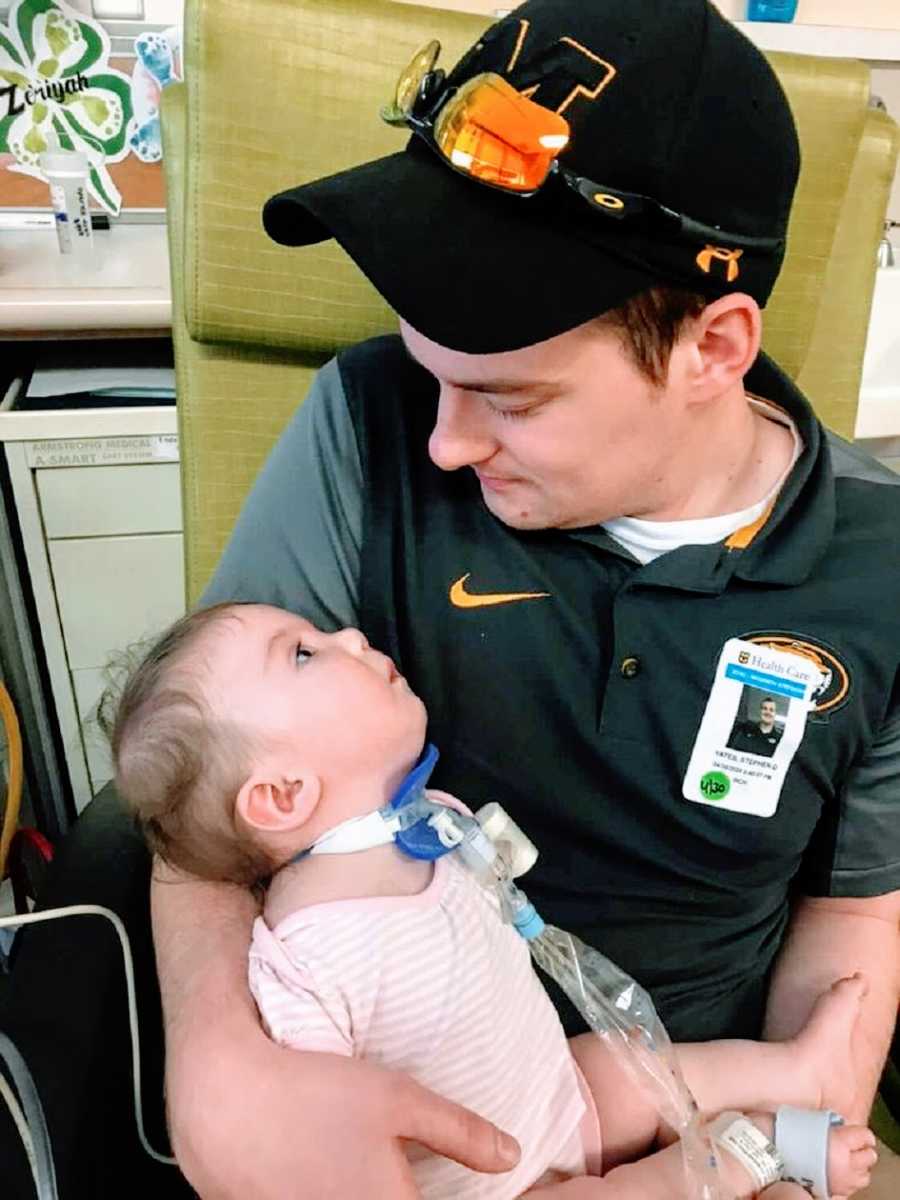 A man sits holding his adopted baby daughter