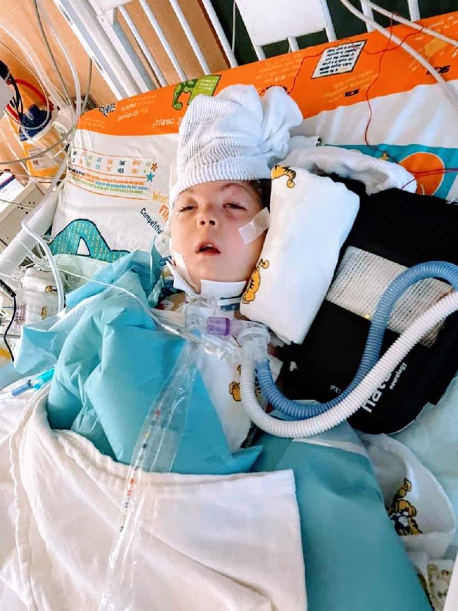 A little girl lying in a hospital bed attached to several tubes