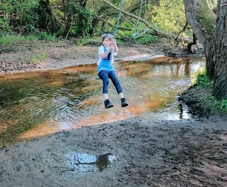 A girl with autism plays on a swing over water