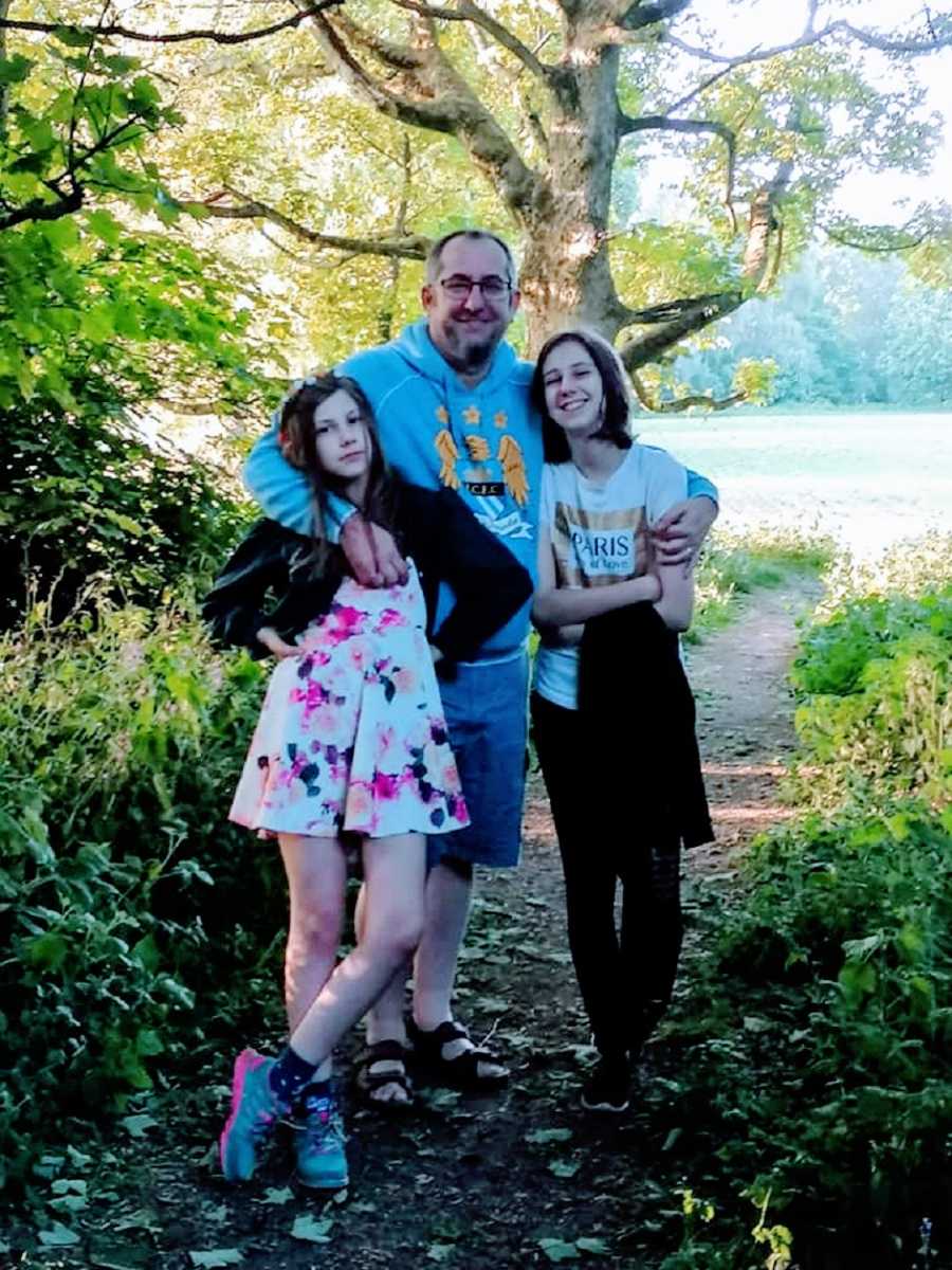 A father stands with his two children outdoors