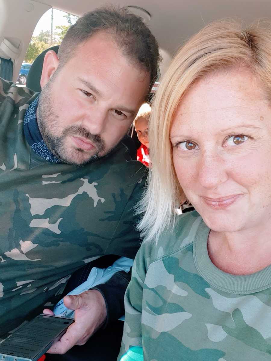 A woman and her husband wearing camouflage sit in their car 