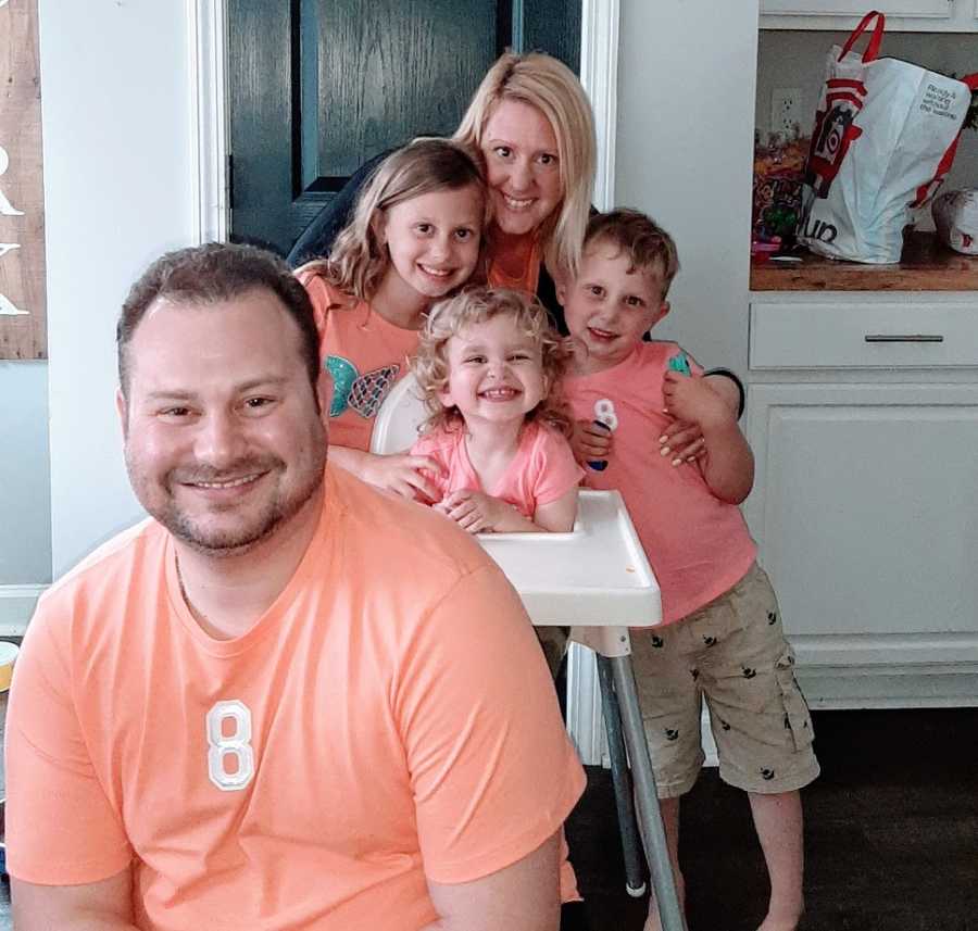 A woman with her three children and her husband, all dressed in orange