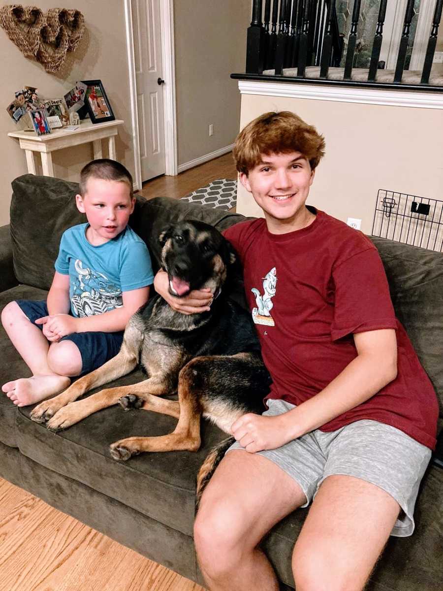 Brothers sit with a dog on the couch