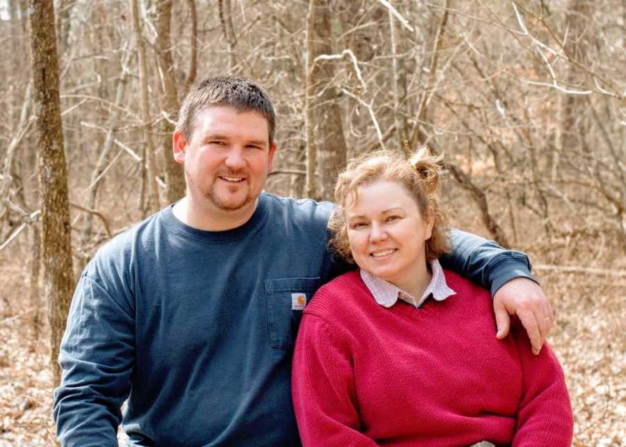 A couple sit together in the woods