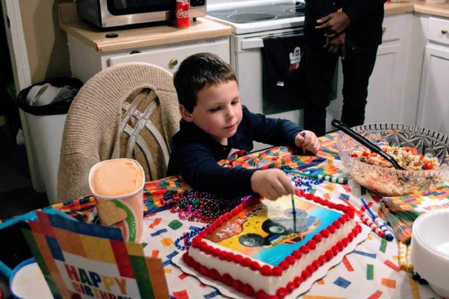 A little boy cuts into a cake on his birthday