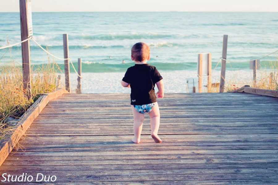 A toddler runs down a dock towards the water