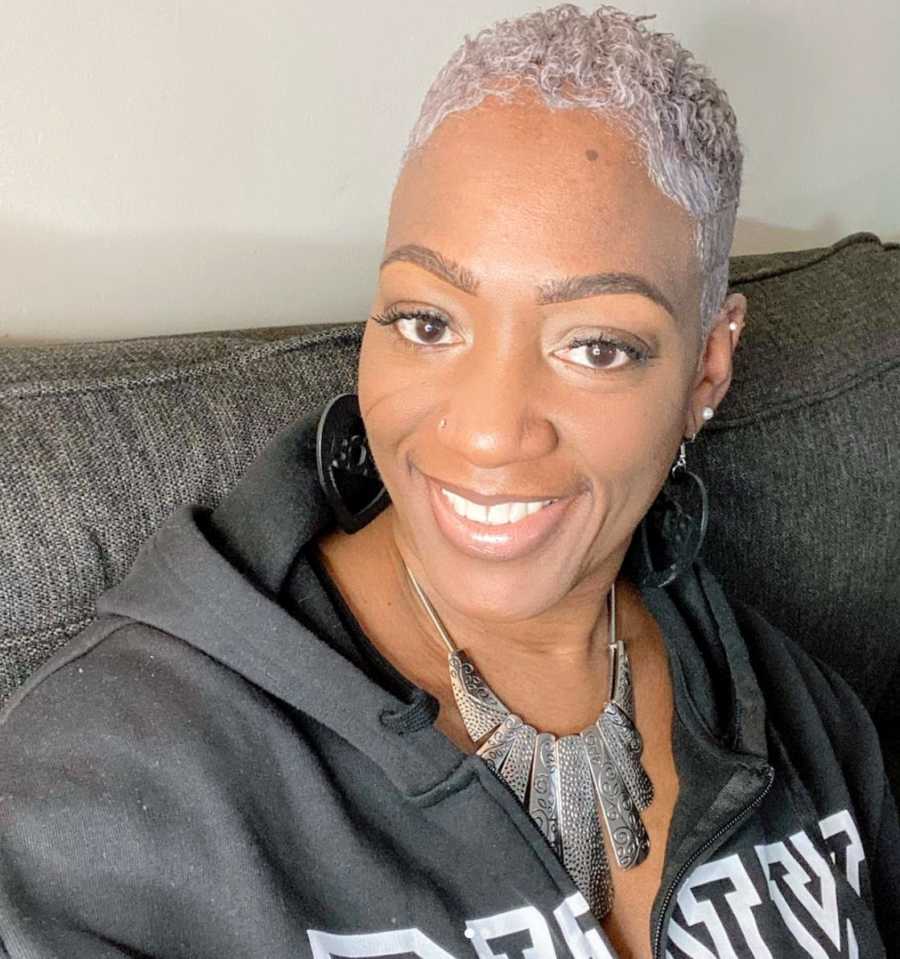 A woman with grey hair sits alone on a couch